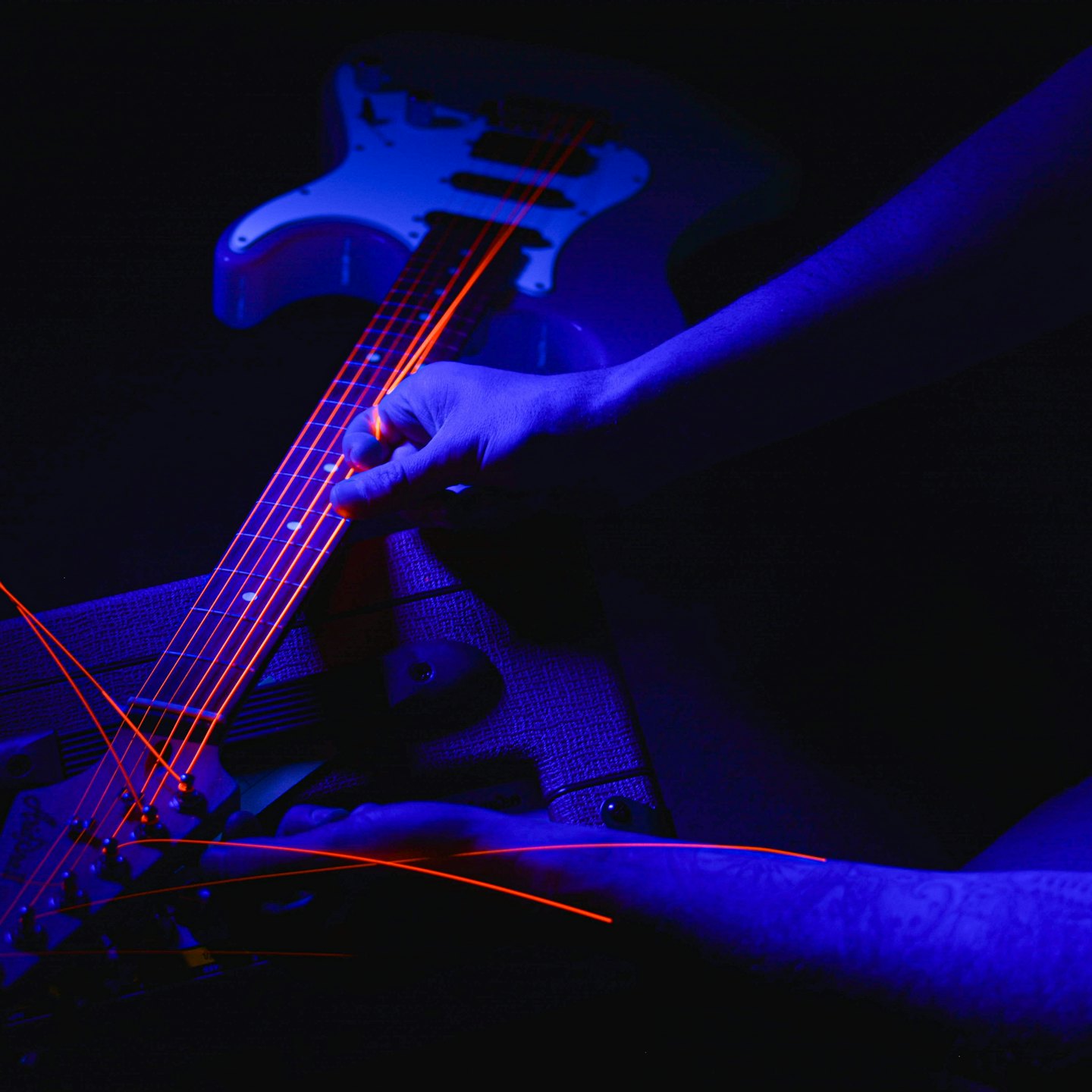 Hands playing electric guitar with glowing strings.