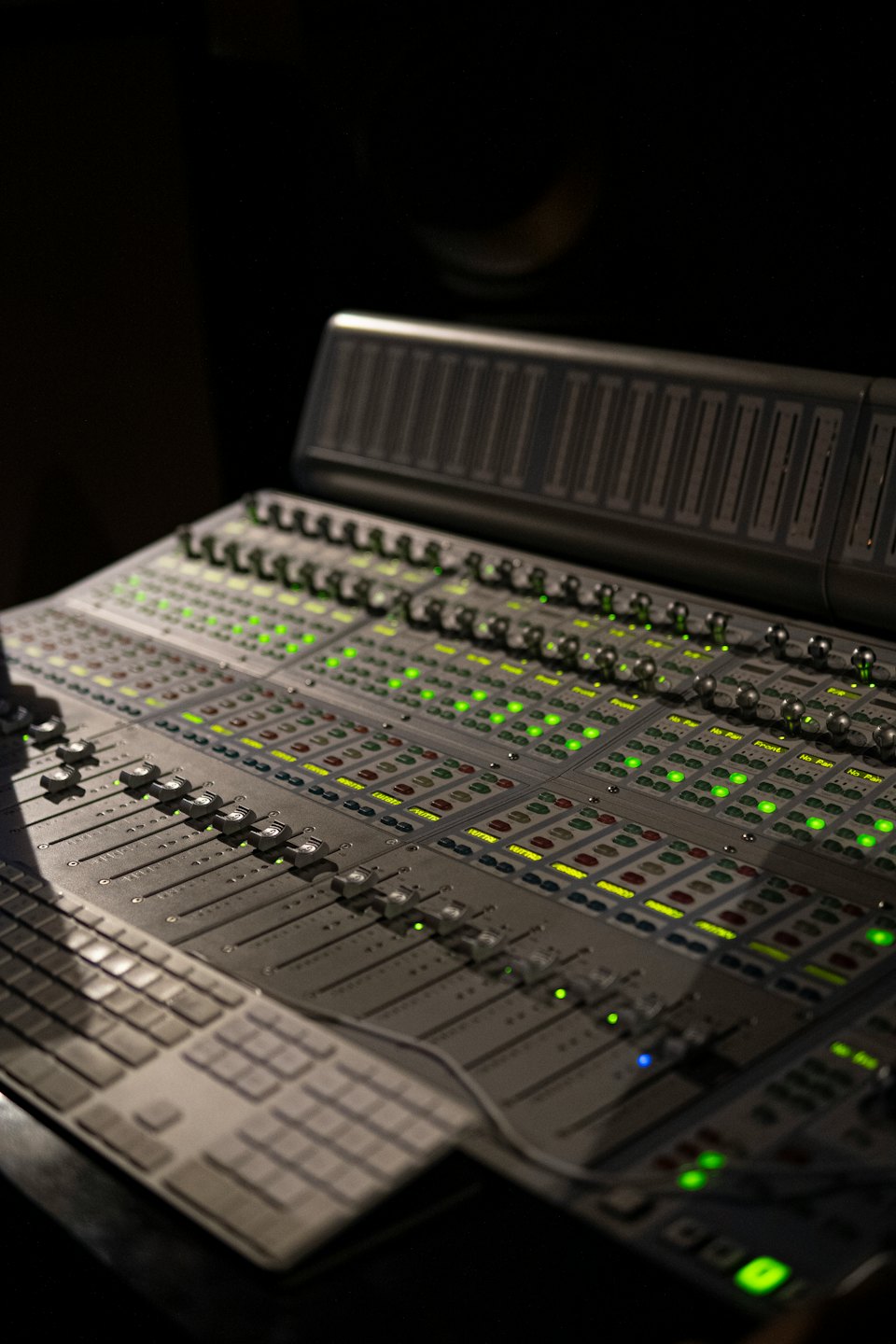 Professional audio mixing console with illuminated buttons and faders.
